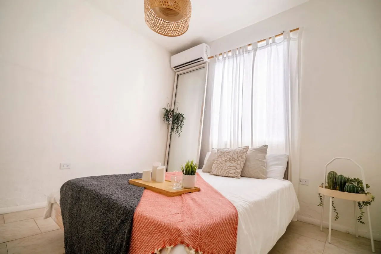 Bedroom with a bed, a mirror, and a potted plant — Sunset Haven | Ocean Breeze | Old San Juan, Old San Juan