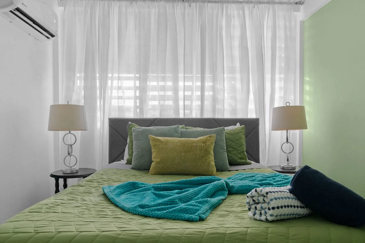 Bedroom with a blue blanket on the bed and a green wall — Maré 2BR | Near Ocean Park Beach + Laundry, Santurce