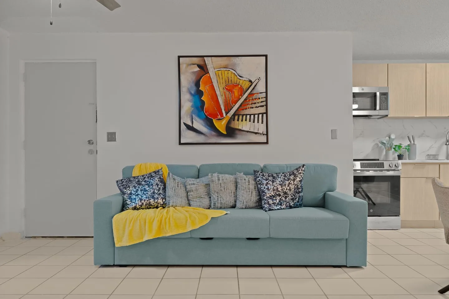 Blue couch with pillows and a painting on the wall — San Juan 2BR | Sleeps 7 + Balcony & Laundry, Santurce