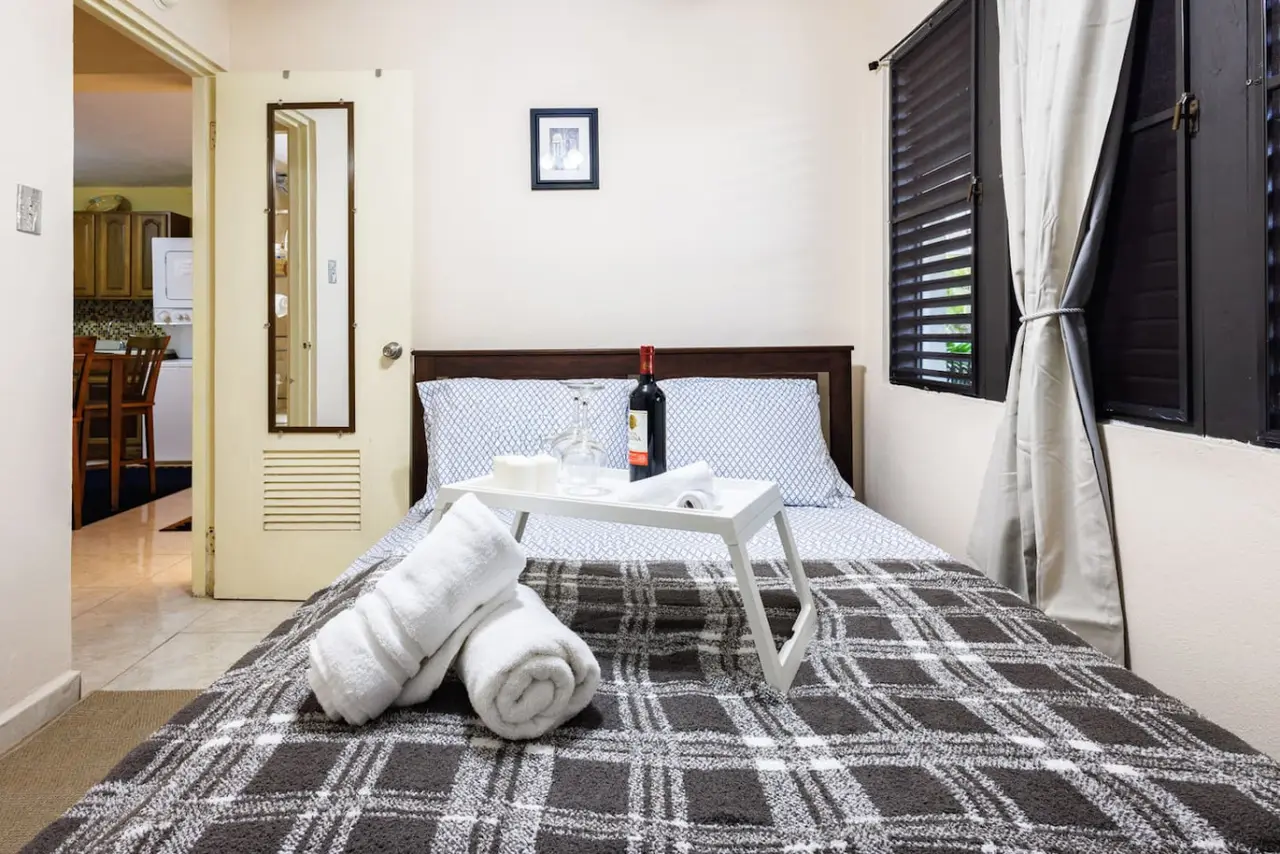 Bedroom with a bed, a table with a bottle of wine and a towel on it — Ocean Sol Historic Old San Juan