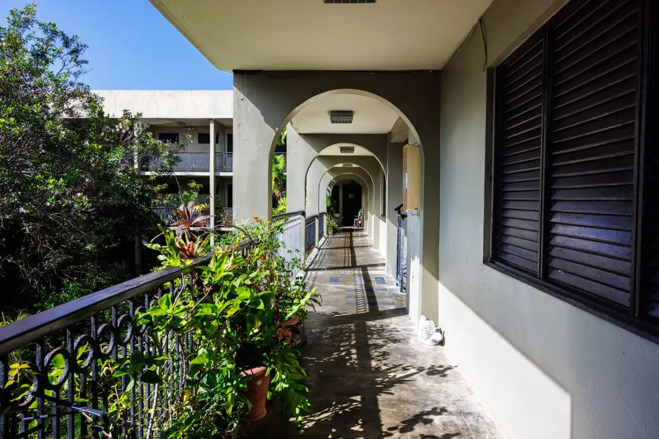 Building's arched open-air walkway with potted plants — Ocean Sol Historic Old San Juan