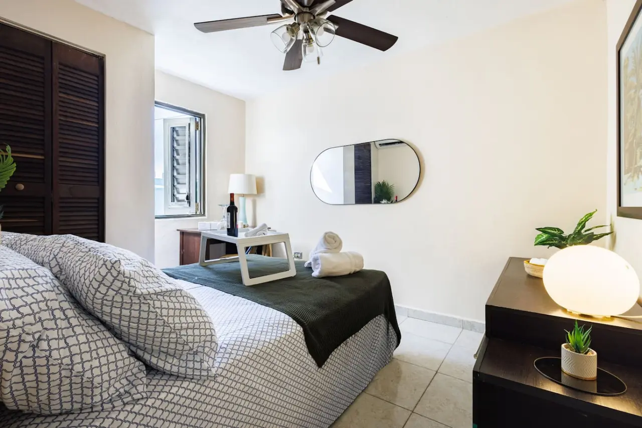 Bedroom with louvered closet doors and an oval mirror — Ocean Sol Historic Old San Juan