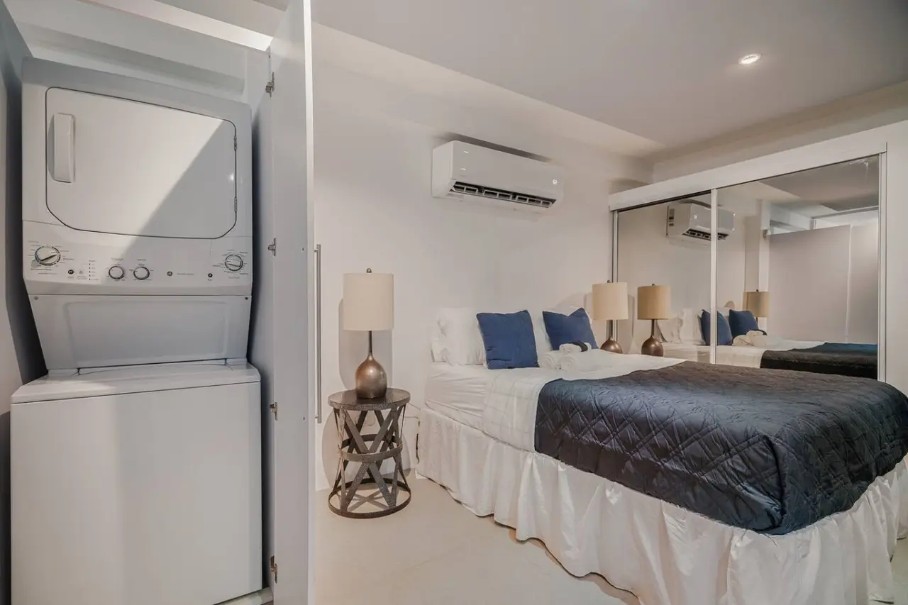 Sleeping area with a bed and a stacked washer and dryer — Punta Las Marias Studio - Short Walk to the Beach, Santurce