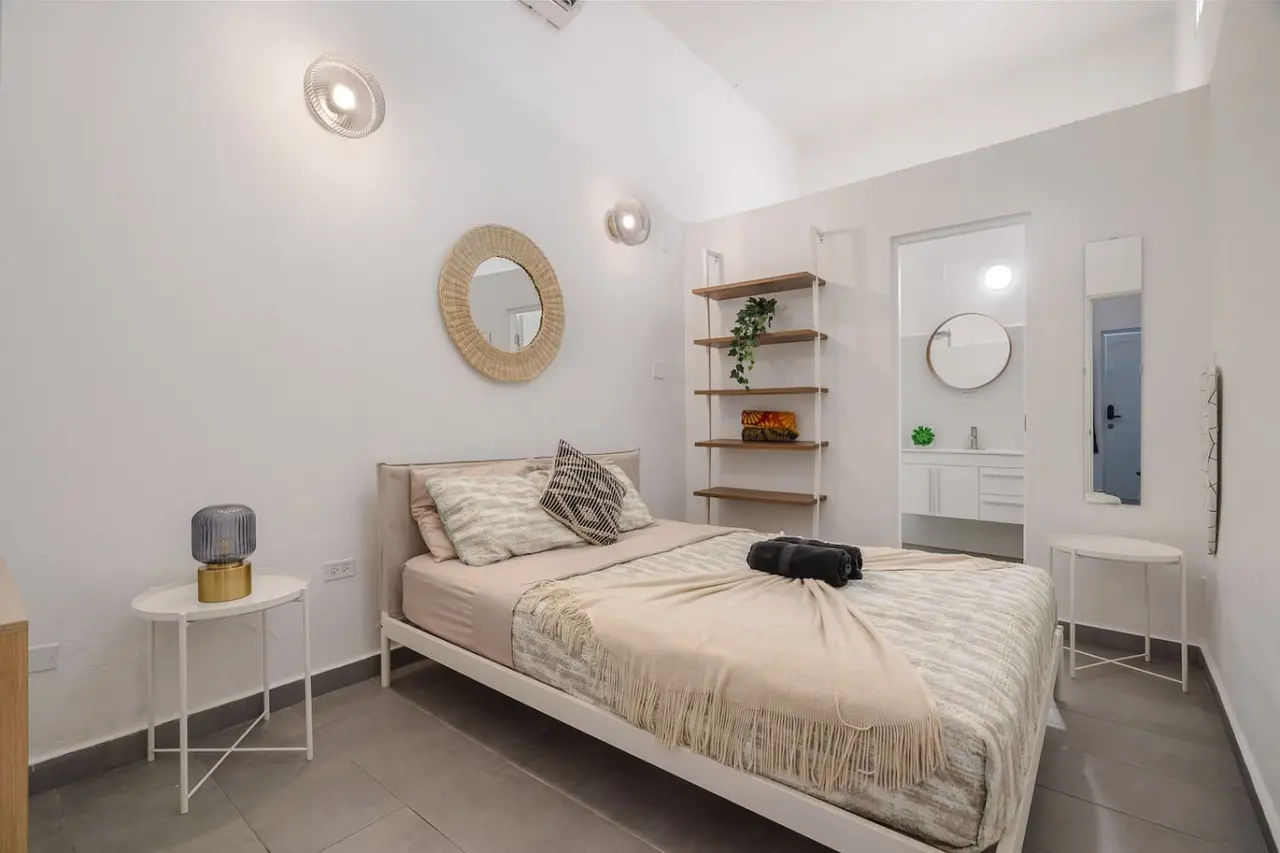 Bedroom with a white bed and a mirror on the wall — Downtown San Juan Gateway Dream, Santurce