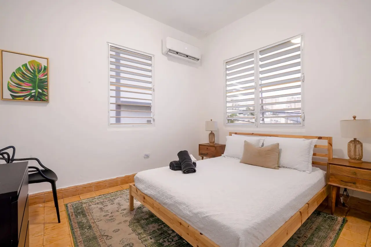 Bedroom with a bed, nightstand, and a window — Luz Collection No.3 – Casa Horizonte | 3BR Loft, Santurce