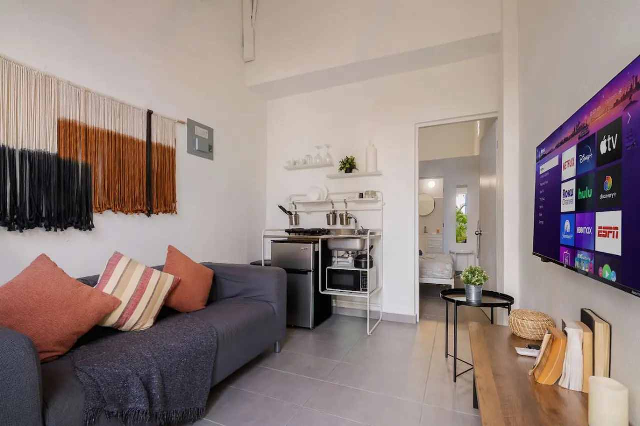 Living room with a sofa, TV and the kitchenette behind — Downtown San Juan Gateway Dream, Santurce