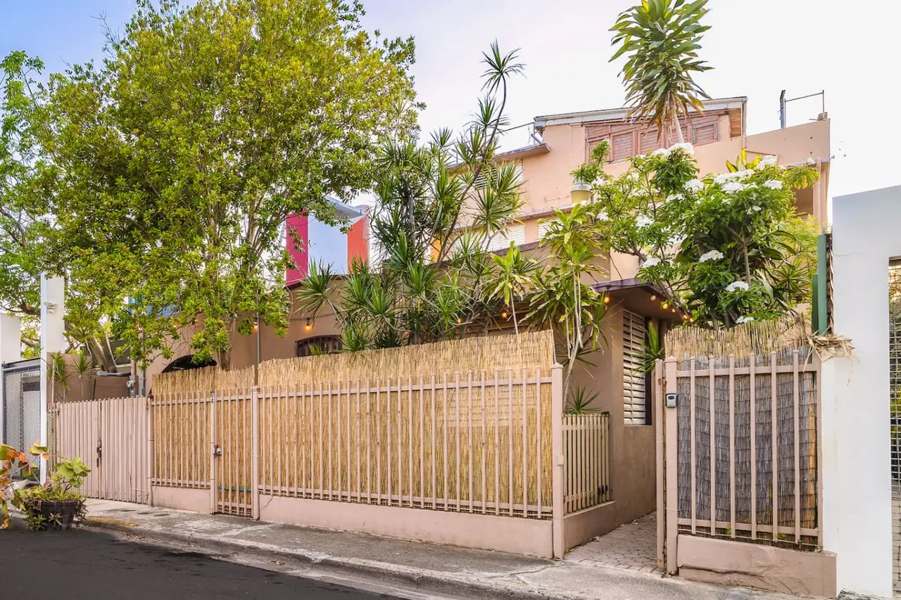 Building behind a reed fence and trees — Tapia Mosaic Beachwalk - San Juan, Santurce