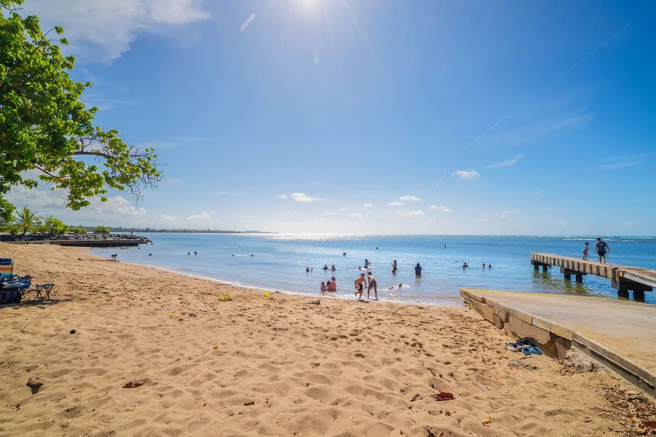 Sandy beach with a pier and people swimming — Beach Villa Dorado Del Mar