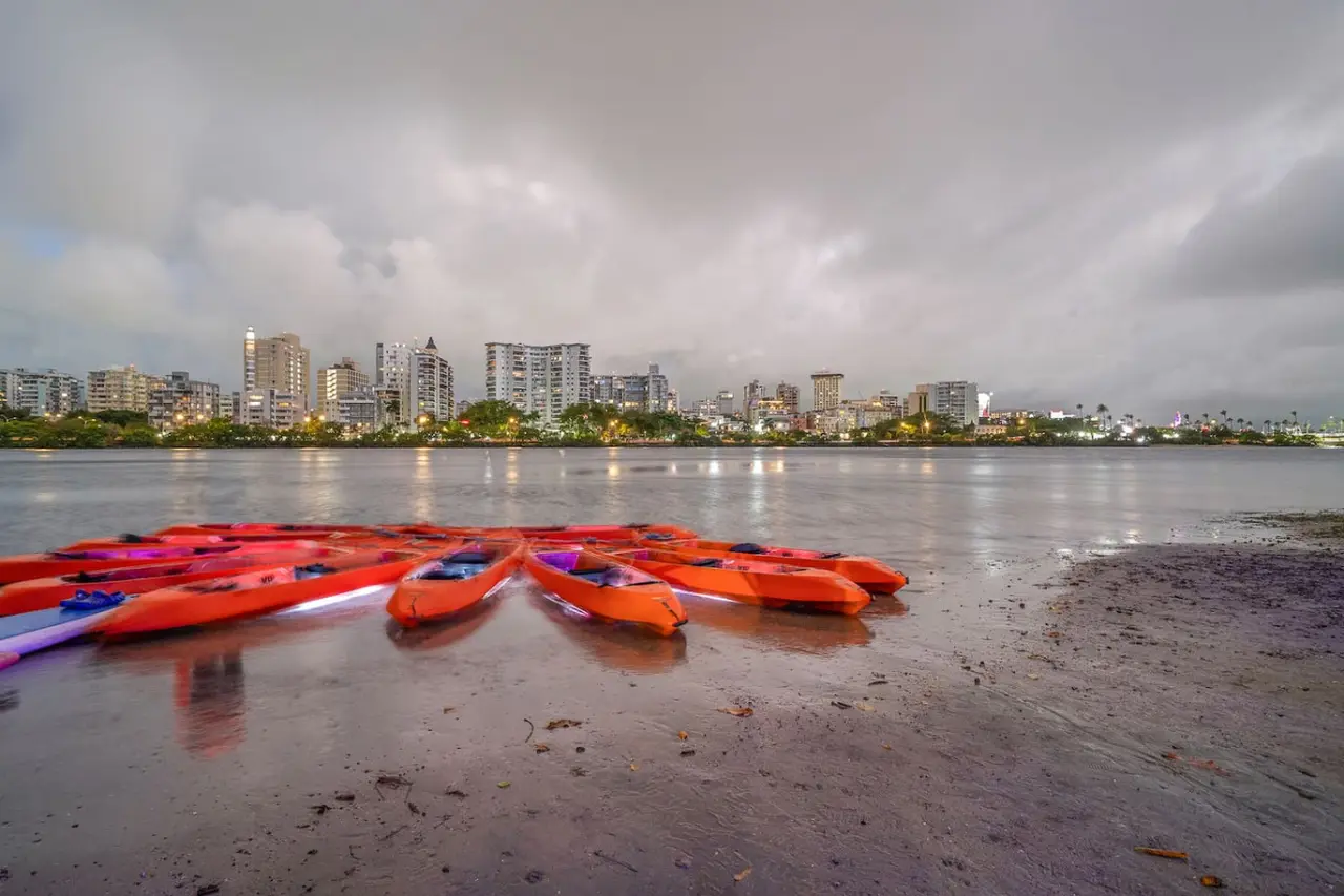 Red kayaks on the lagoon shore with the city skyline — Condado Penthouse