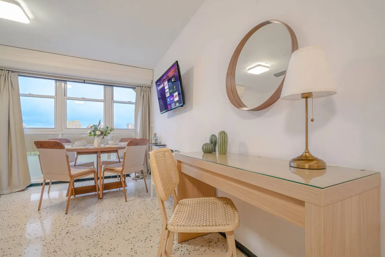 Dining room table with chairs and a TV in the background — Condado Penthouse