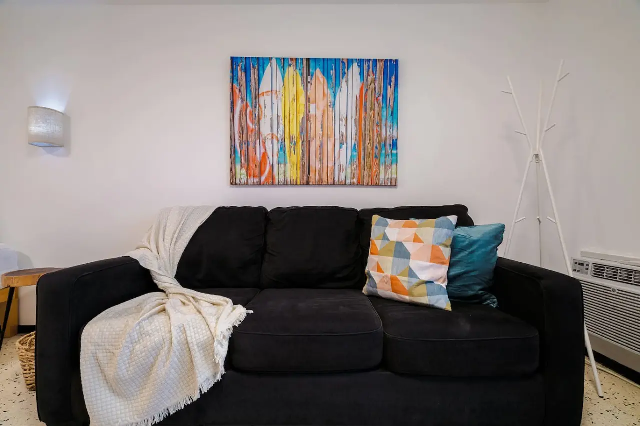 Living area with a black sofa and a colorful painting — Condado Penthouse
