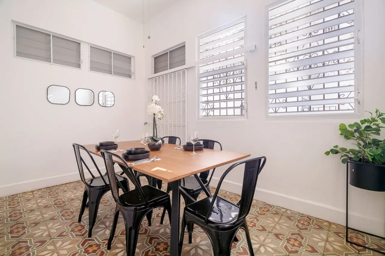 Wooden dining table with chairs and a vase of flowers on it — Luz Collection No.2 – Casa Brisa | 3BR Retreat, Santurce