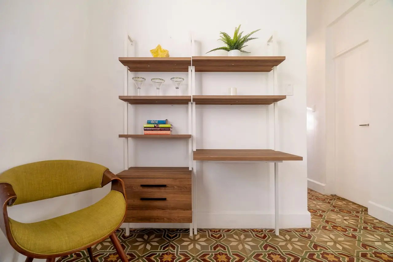 Living room corner with shelves, a desk and a yellow chair — Luz Collection No.2 – Casa Brisa | 3BR Retreat, Santurce