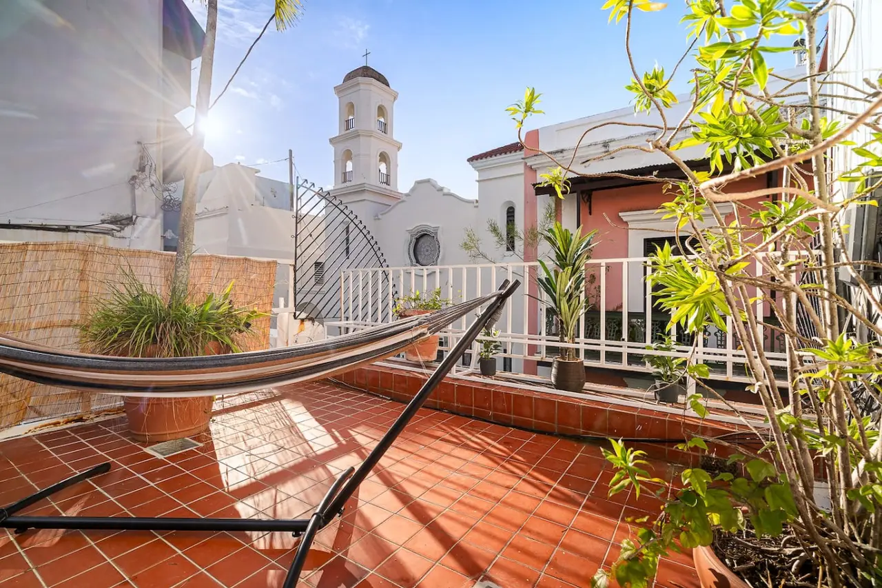 Rooftop terrace of an Old San Juan vacation rental we host, with a hammock and a church bell tower beyond