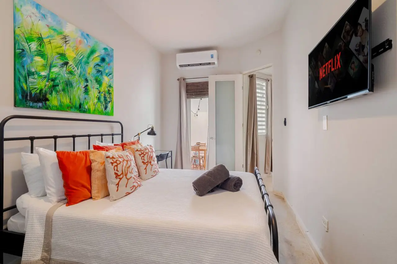 Bedroom with an iron bed, a wall TV and a patio door — Historical Old San Juan Spanish style private Patio
