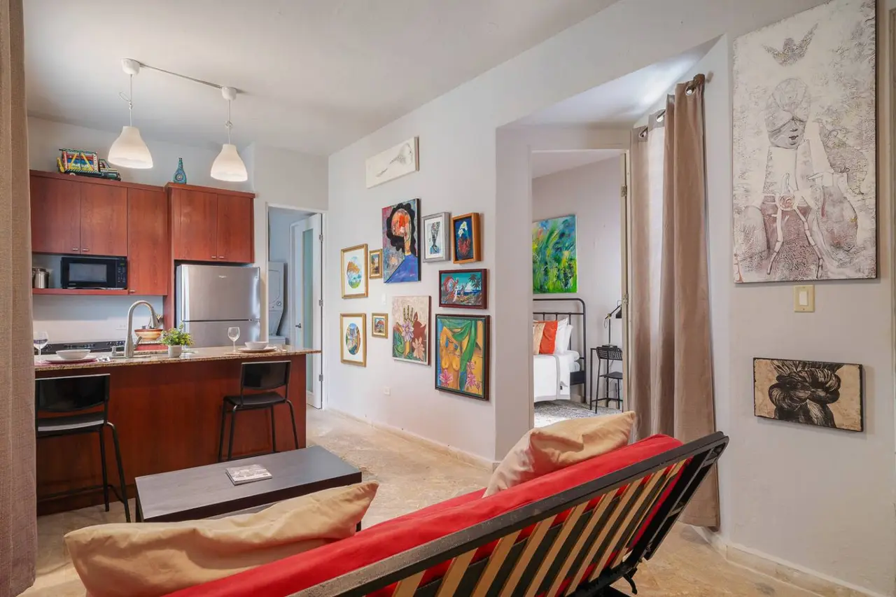 Living room with a red sofa, art wall and open kitchen — Historical Old San Juan Spanish style private Patio