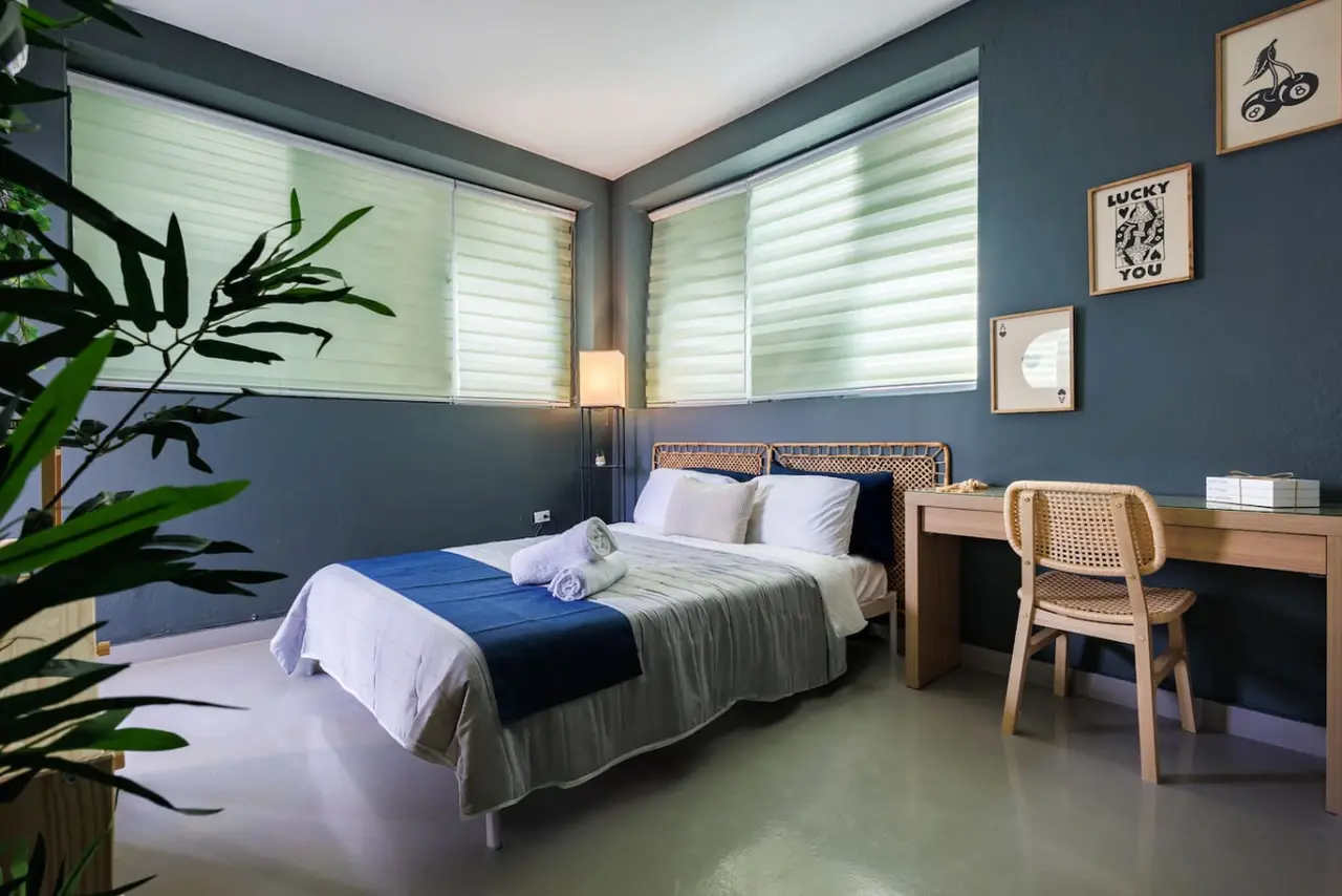 Bedroom with a blue bedspread and white pillows — Spain Lagoon | San Juan | Private Patio, Santurce