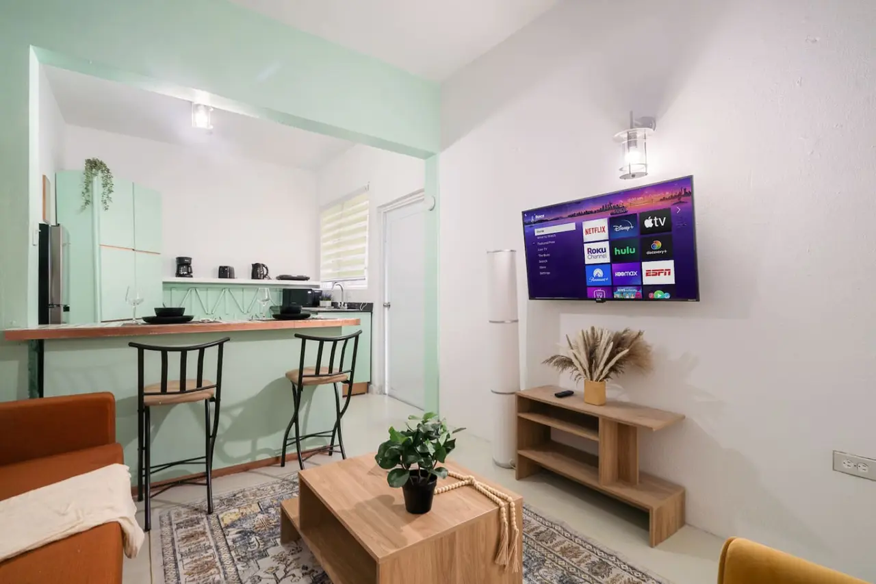 Living area with a TV, open to a mint-green kitchen — Puerto House - Private Patio, Santurce