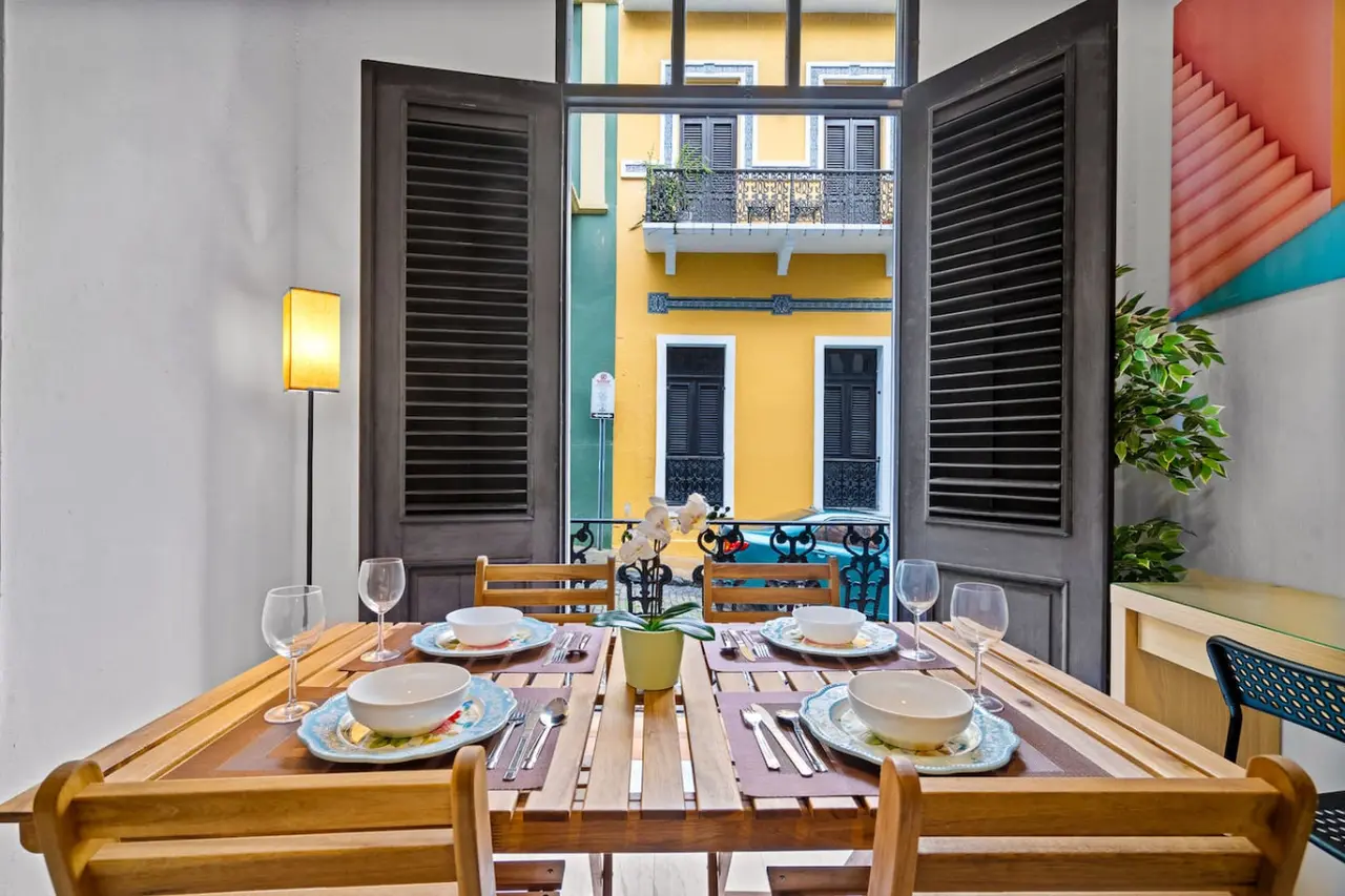 Dining table with chairs and a vase of flowers on it — El Balcón Art Loft – Old San Juan