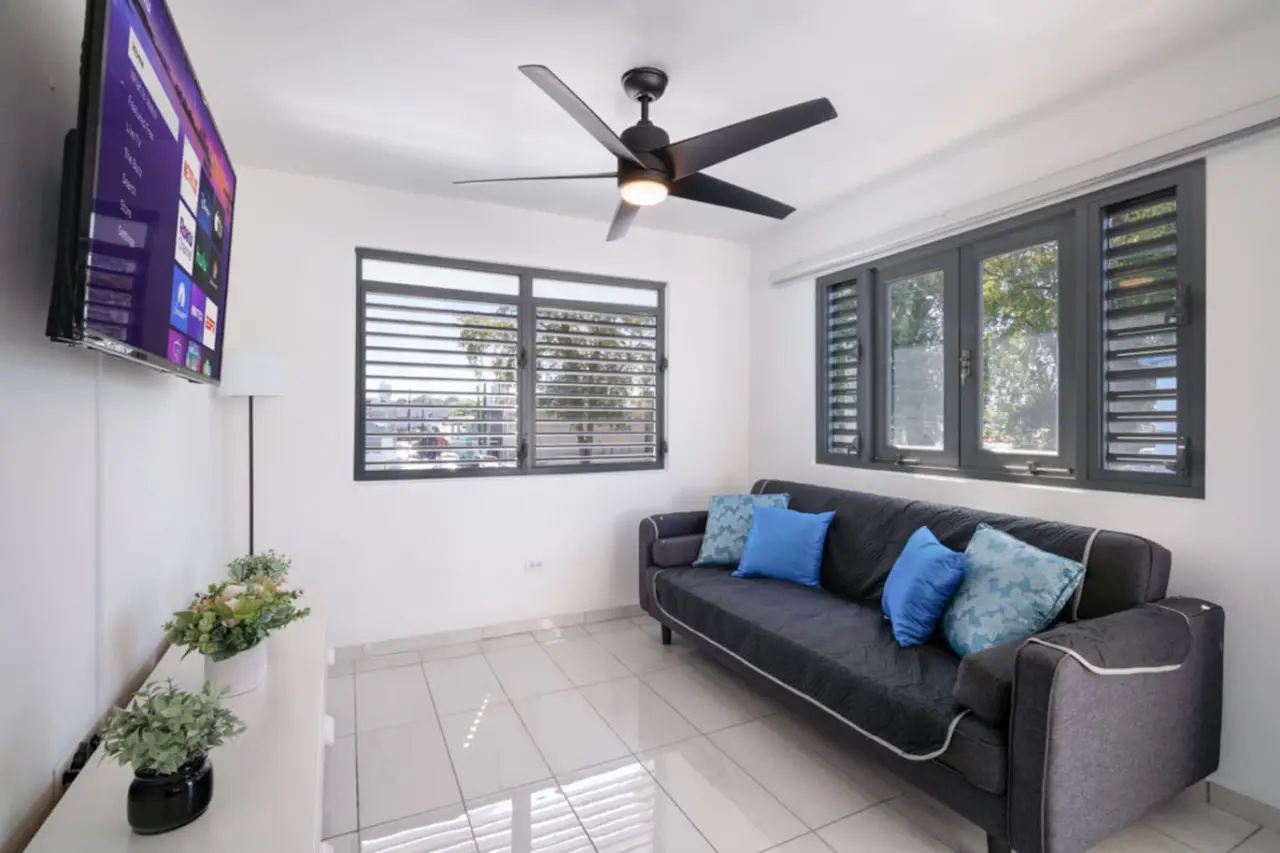 Living room with a gray sofa and a wall TV — Casa Juno Grand Modern - 3 Bedroom - Walk to Beach, Santurce