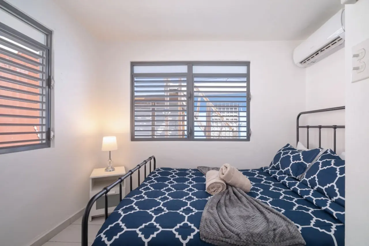 Bedroom with a black metal bed and navy patterned bedding — Casa Juno Grand Modern - 3 Bedroom - Walk to Beach, Santurce