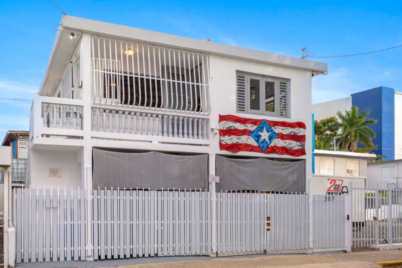 White house with a balcony and a flag hanging from it — Casa Juno Grand Modern - 3 Bedroom - Walk to Beach, Santurce