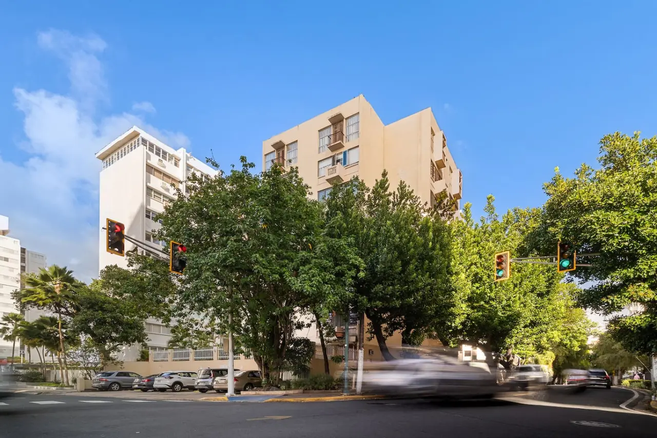 Building seen from the street, behind trees — Luxe Beachside Oasis: Pool Parking & Generator, Santurce