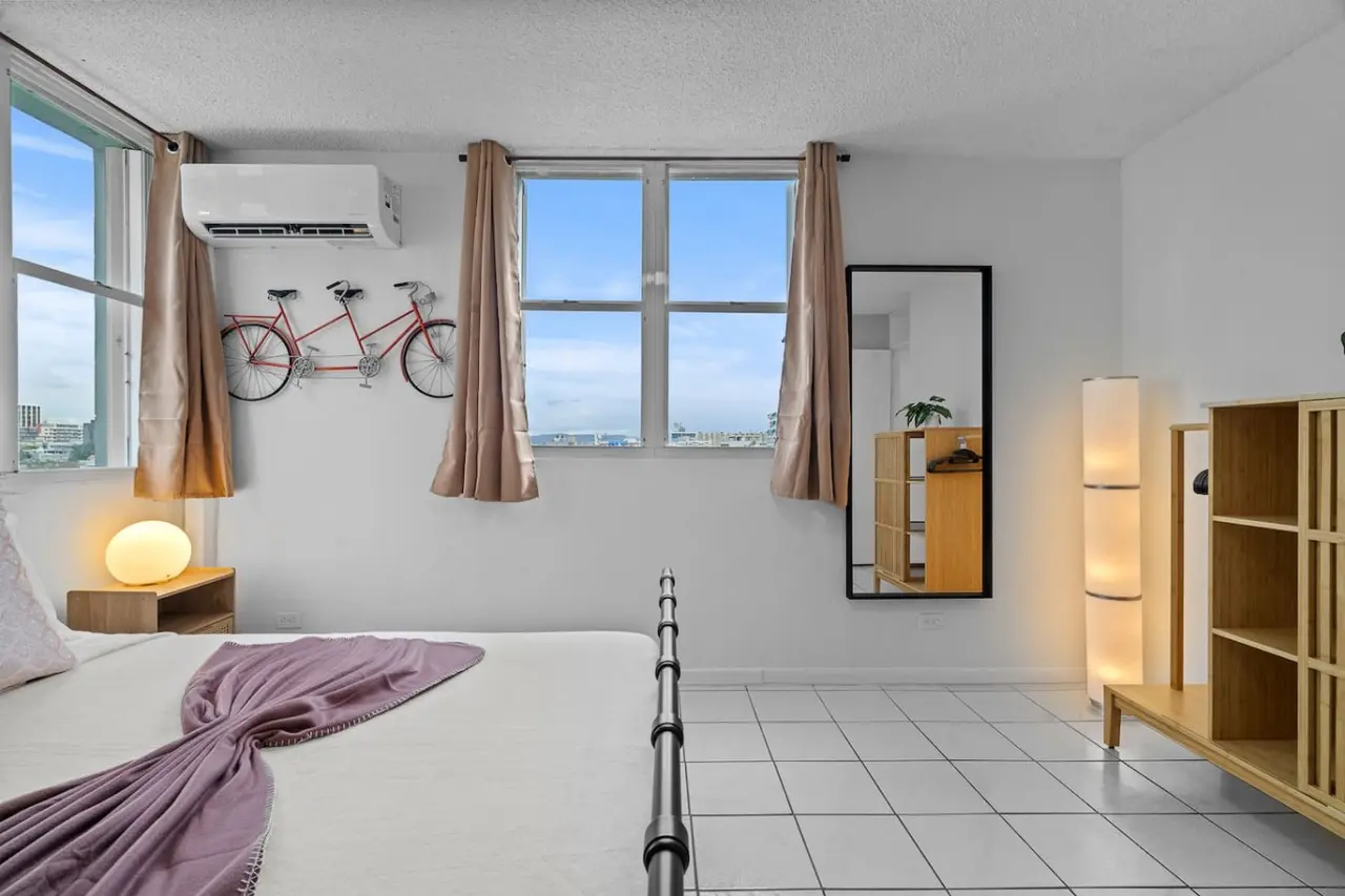 Bedroom with a bed and a bicycle hanging on the wall — High-Rise Condado Suite | Ocean Views & PR Skyline