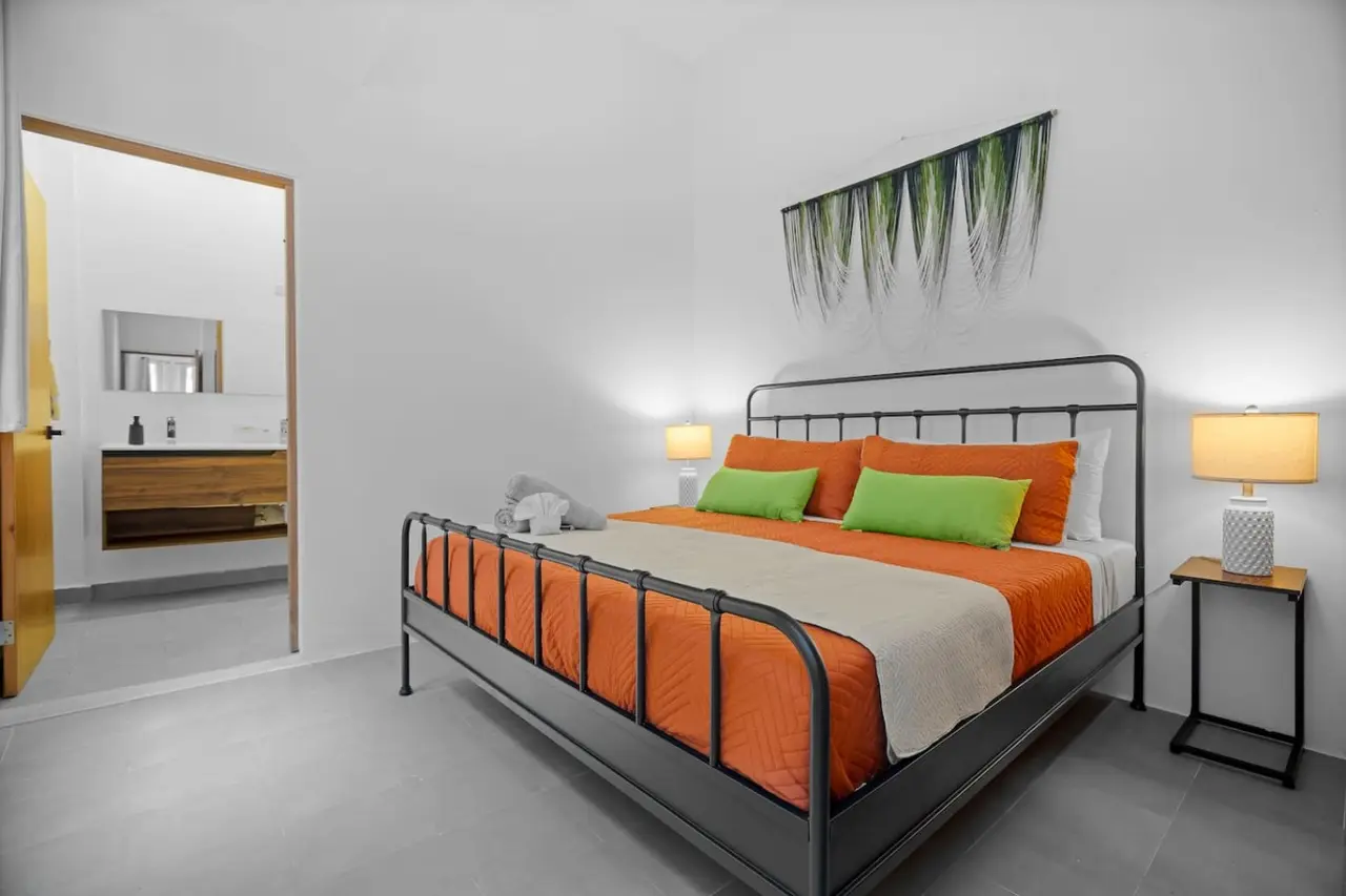 Bedroom with a black metal bed frame and orange pillows — Bellavista Galleria | Old San Juan