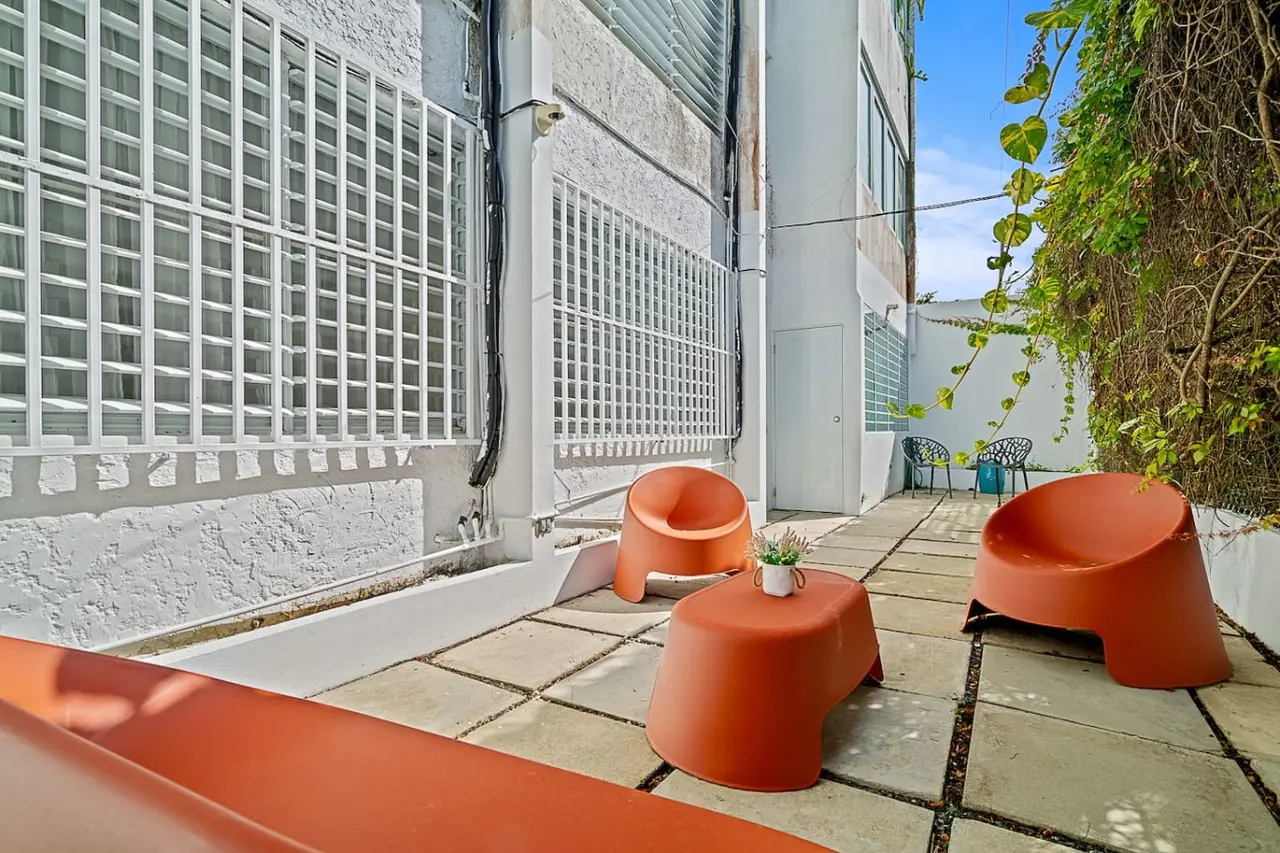 Patio with orange lounge chairs along the building — Ocean Park 2BR Backyard BBQ Walk to Beach, Santurce