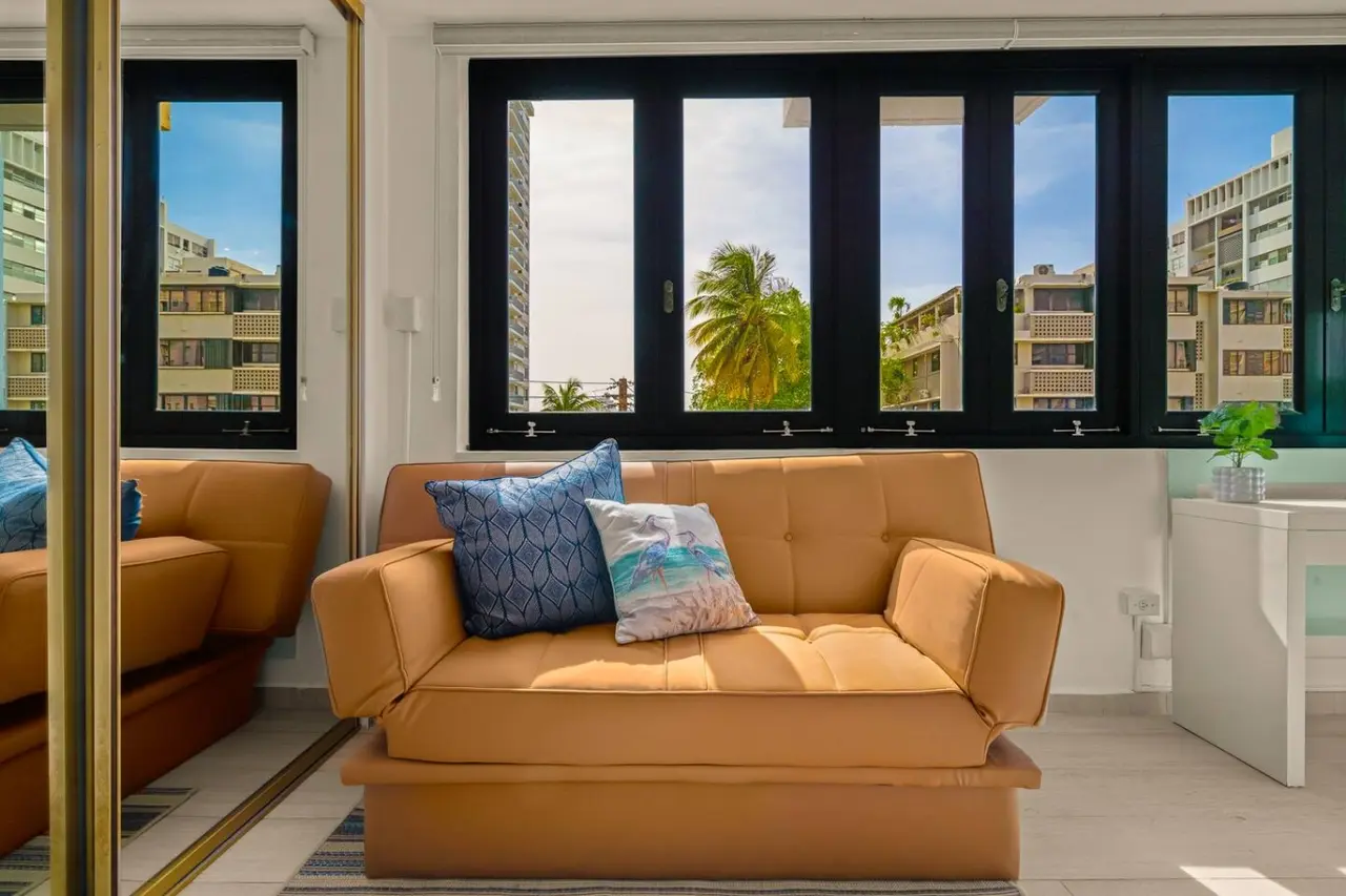 Living area with a tan sofa bed by the windows — Casa Celeste | Sunlit Tropical Stay in Condado, Santurce