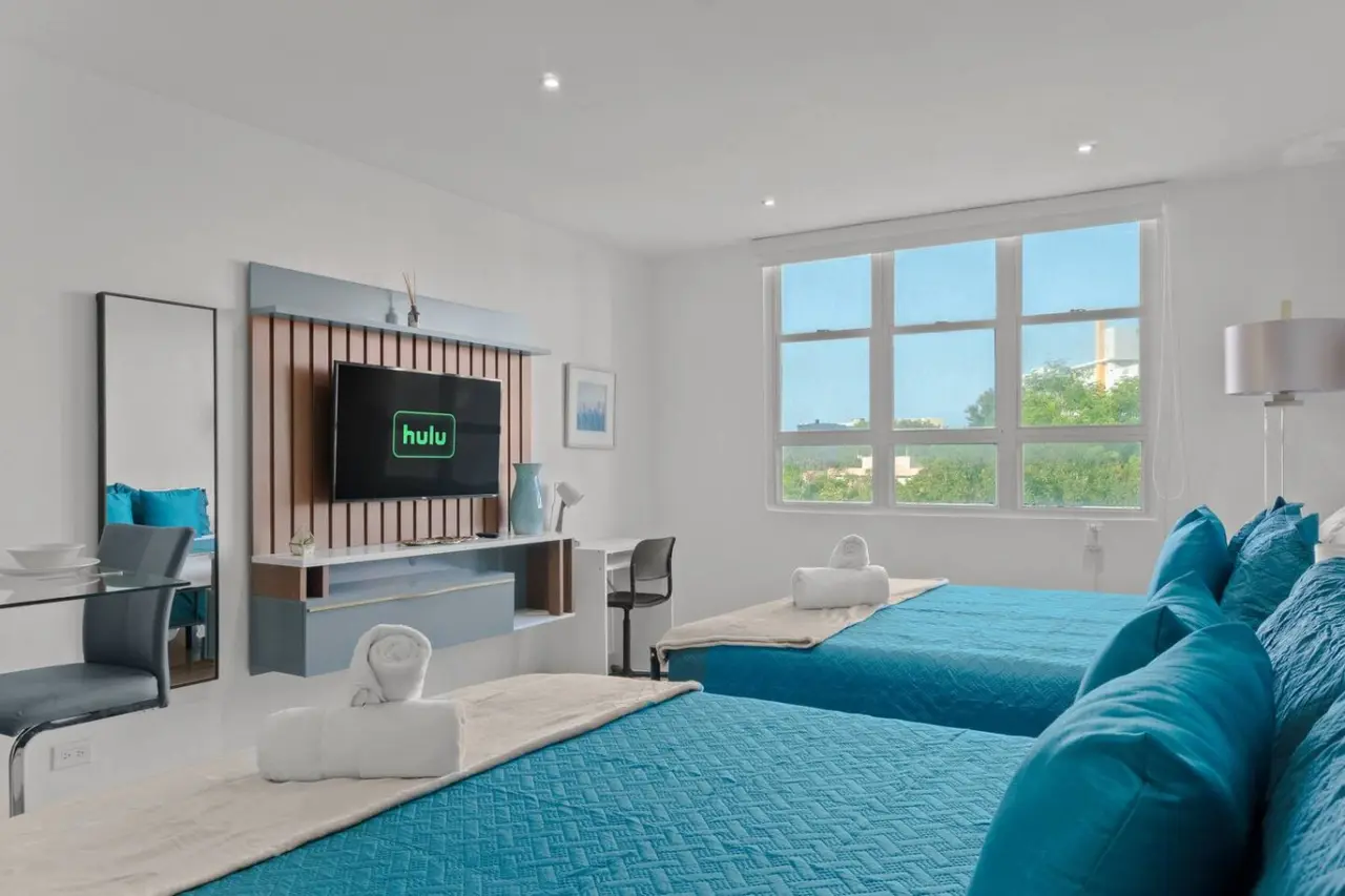 Bedroom with two beds facing a TV wall and a window — T-Mobile District San Juan Next to Beach