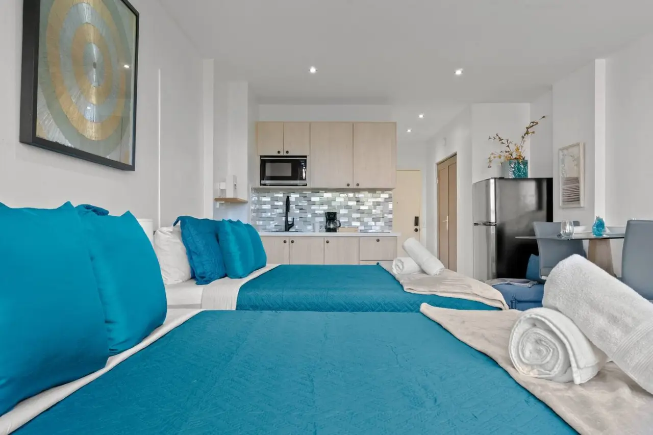 Bedroom with two beds, the kitchenette beyond — T-Mobile District San Juan Next to Beach
