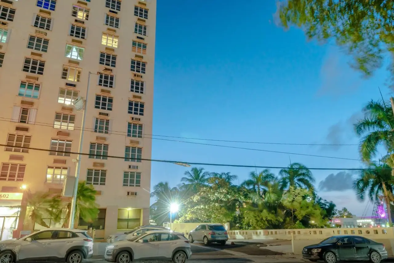 Street lined with high-rises and palm trees at dusk — T-Mobile District San Juan Next to Beach