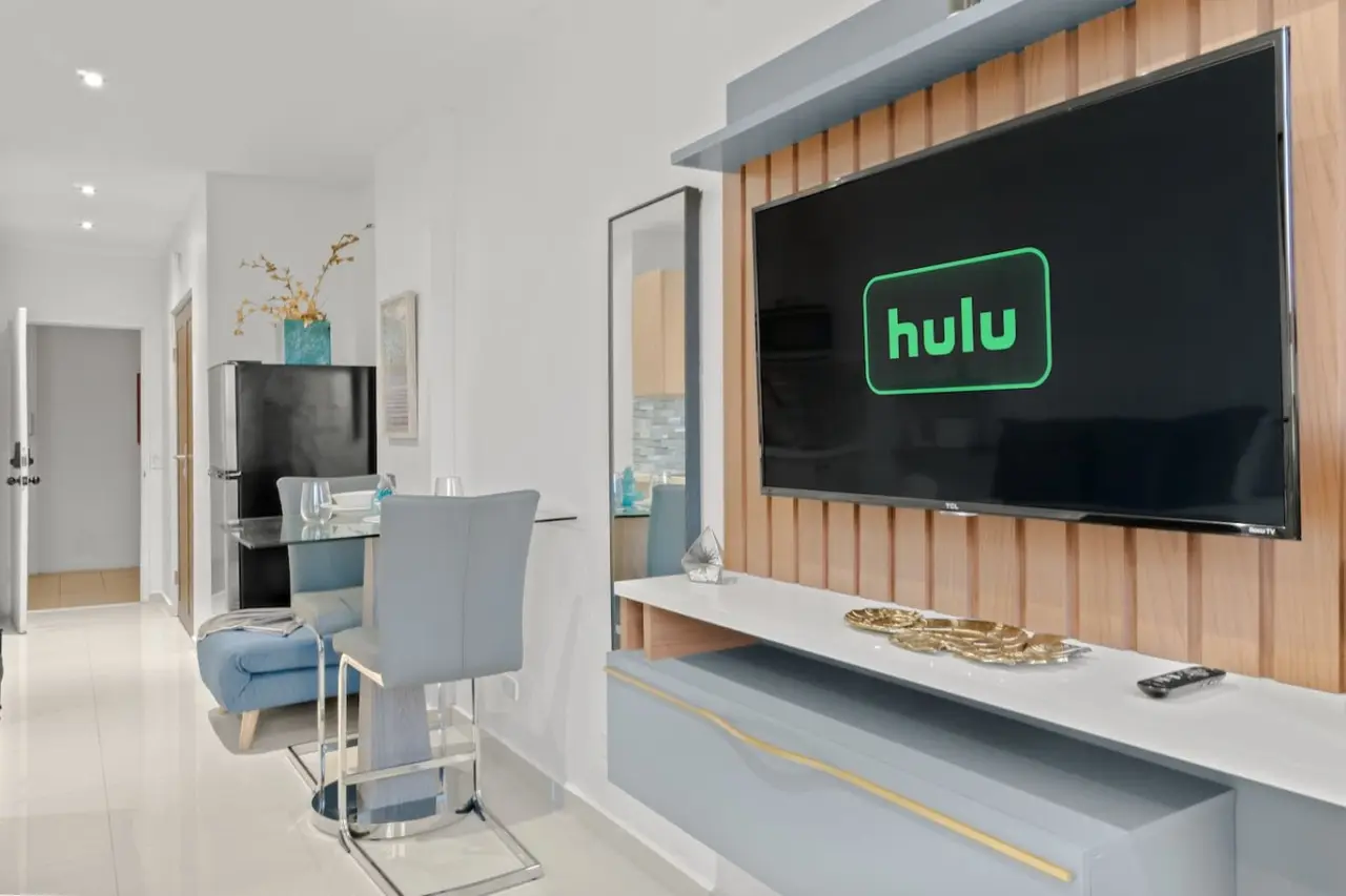Living area with a TV wall, a dining table and a fridge — T-Mobile District San Juan Next to Beach