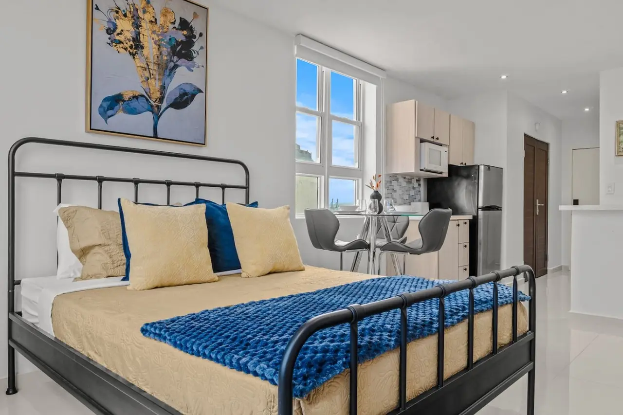 Bedroom with a blue bedspread and yellow pillows — Caribbean Sea View | T-Mobile District Free Parking, San Juan