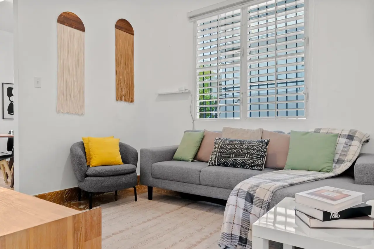 Living room with a gray sofa and two fringed wall hangings — Aurelia | Three Bedrooms in the Heart of San Juan, Santurce