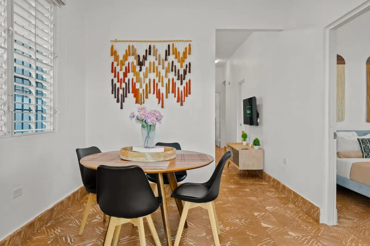 Dining table with chairs and a vase of flowers on it — Aurelia | Three Bedrooms in the Heart of San Juan, Santurce