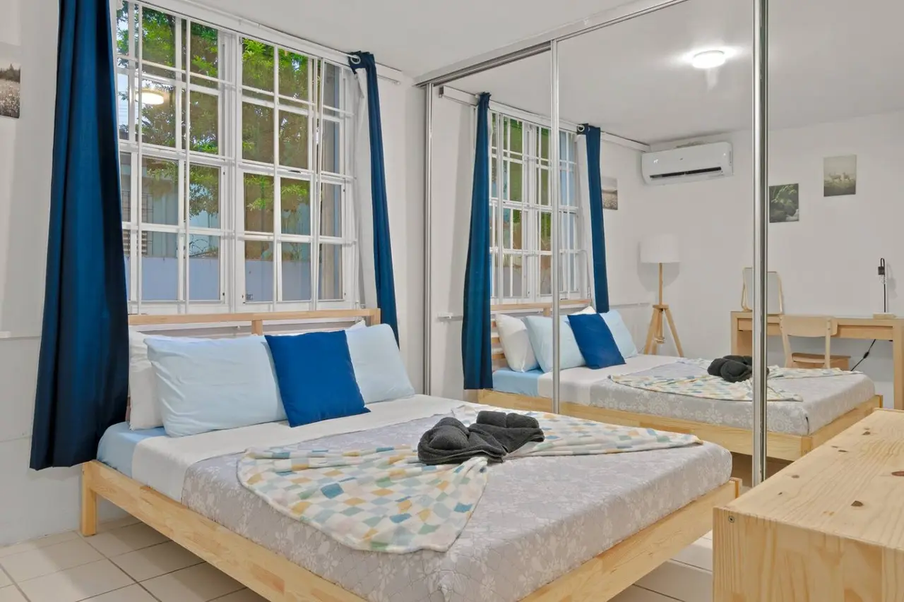 Bedroom with two beds and a window with curtains — The Castillo | Sleeps 8 | 2BR + Backyard & Parking, Santurce