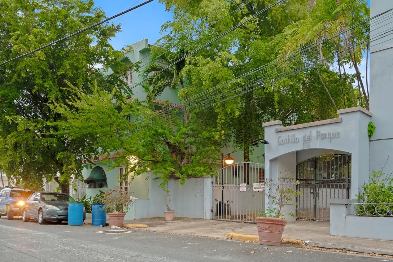 View of the street from the balcony of a green building — The Castillo | Sleeps 8 | 2BR + Backyard & Parking, Santurce