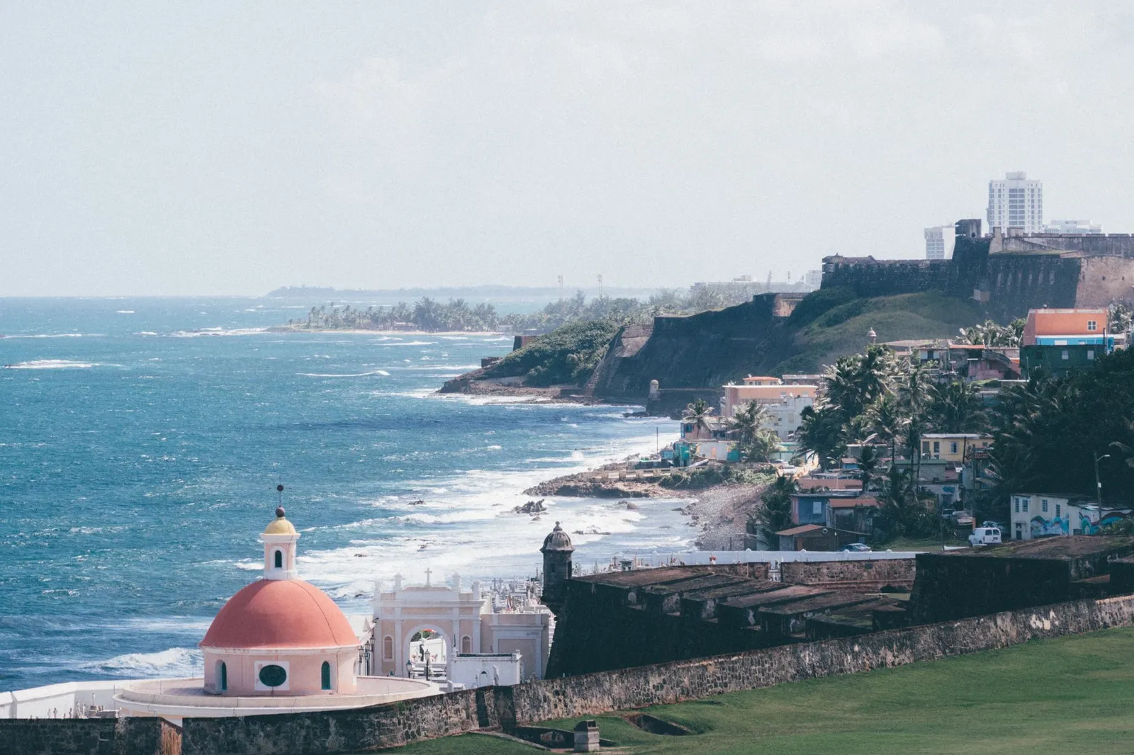 Historic coastal view of San Juan with fortifications and vibrant cityscape by the sea.