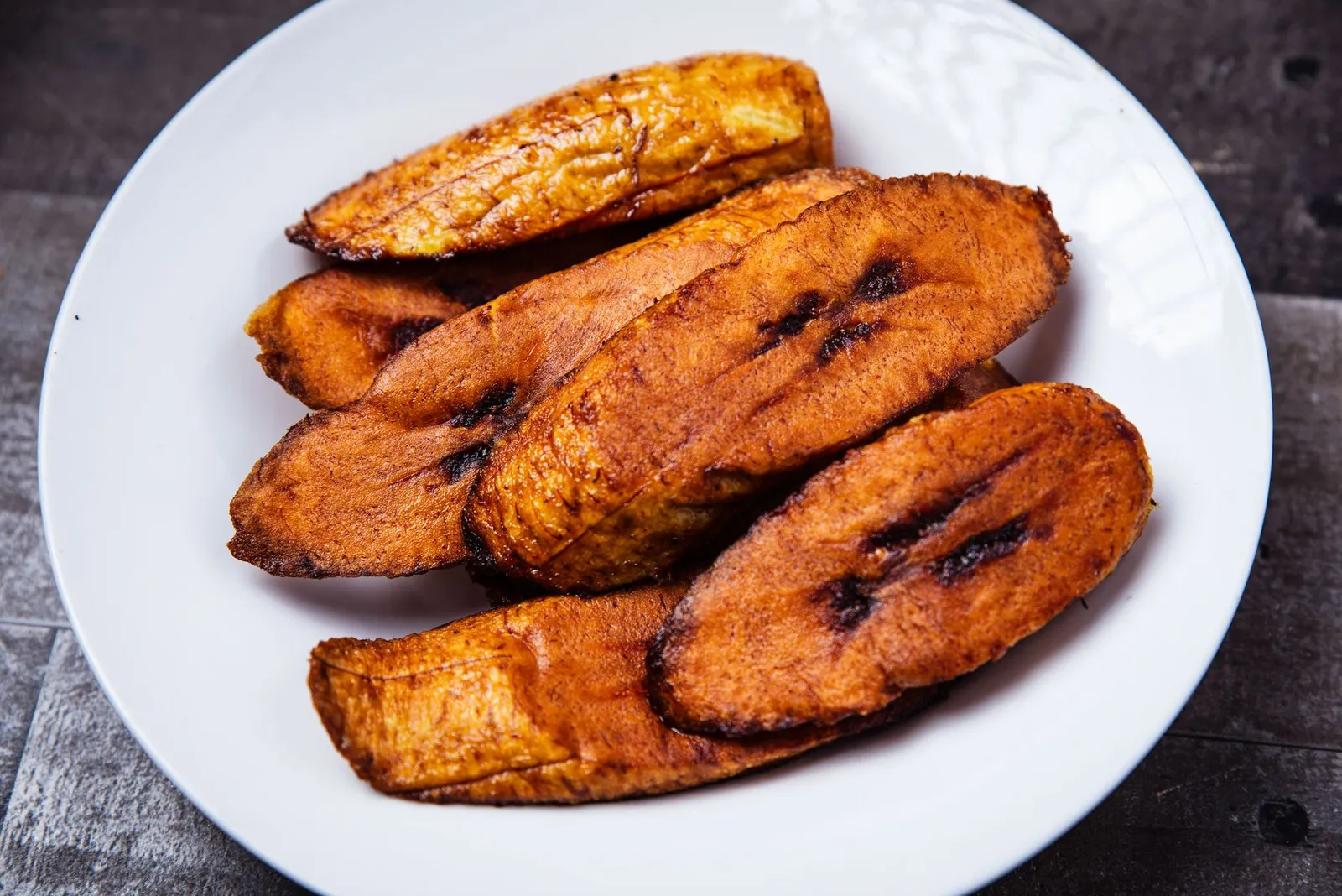 Close-up of crispy fried plantains served on a white plate. Mouth-watering and tasty.