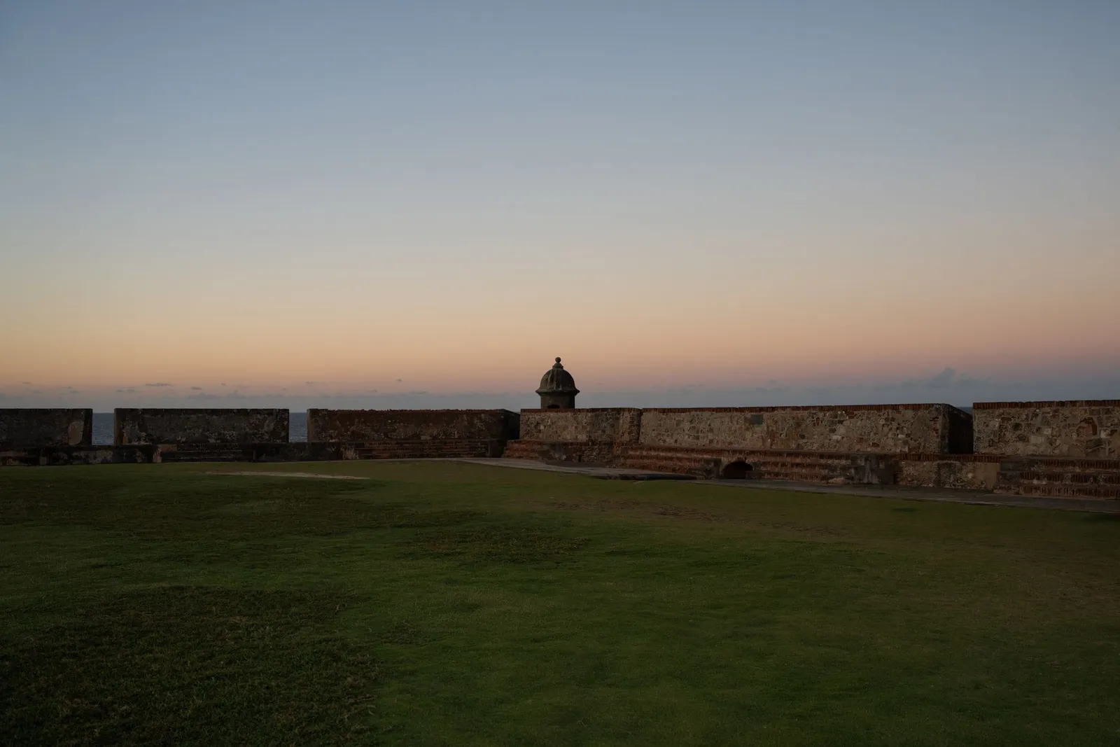 Peaceful sunset view of a historic fort in San Juan, Puerto Rico with clear skies.