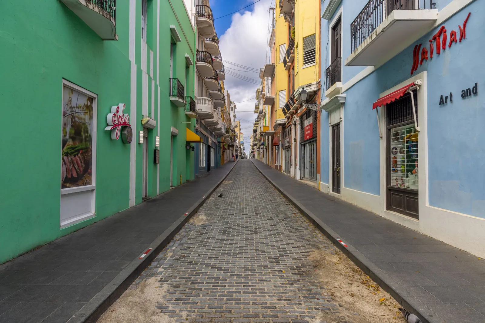 Vibrant and narrow cobblestone street in Old San Juan, showcasing colorful architecture and urban charm.